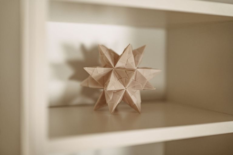 Ein weißer Origamistern in einem weißen Regal