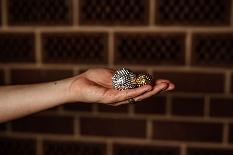 Eine Hand, die eine silberfarbene und eine kleinere goldfarbene Akupressurkugel hält