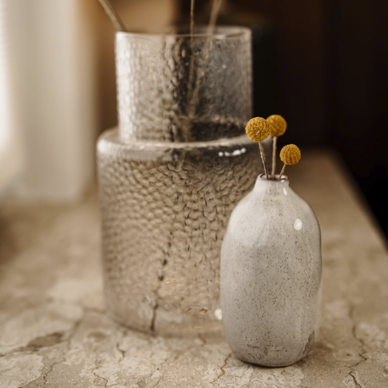 Eine weiße Vase mit drei Trommelstab-Blumen